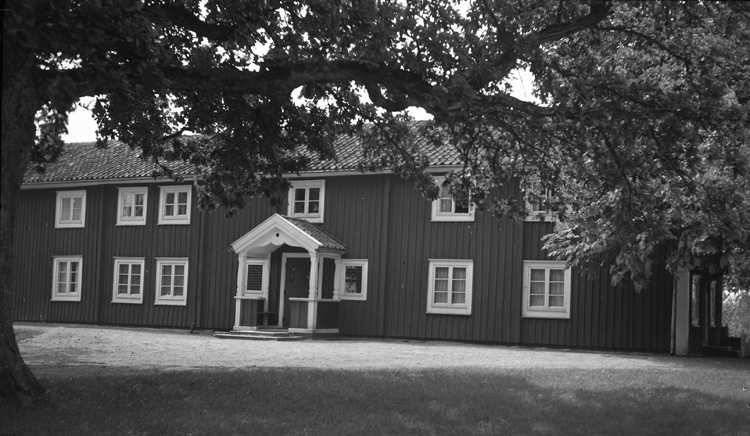 Bostadshus med farstukvist. Ett träd står i förgrunden.