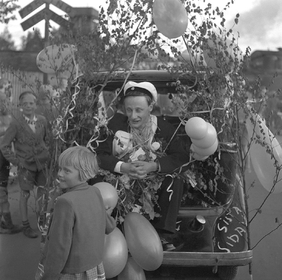 Studenterna första dagen, 1950.
En student körs hem i  bakluckan på en bil, någonstans i
Växjö. 

Angående avgångsklasserna 1950 - se "Lärare och Studenter vid Växjö 
Högre Allmänna Läroverk 1850-1950" (1951), s. 193-196, 289.