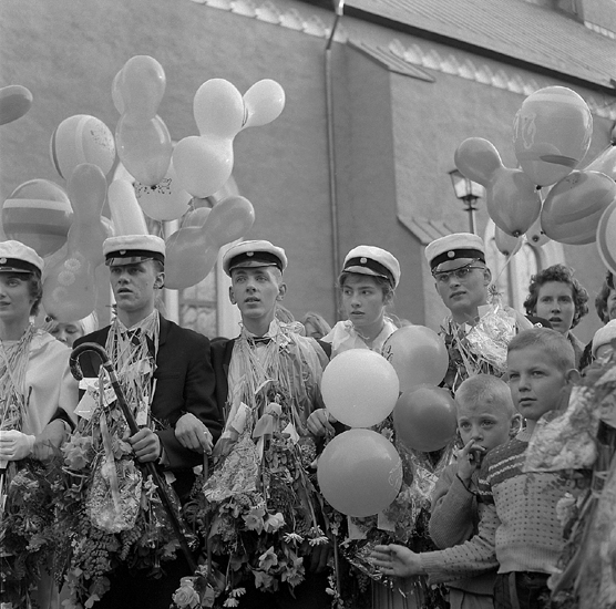 Studenterna, första d. 1960. 
Studenterna har samlats för att lyssna på talet vid Esaias Tegnérs staty. 
I bakgrunden skymtar domkyrkan.