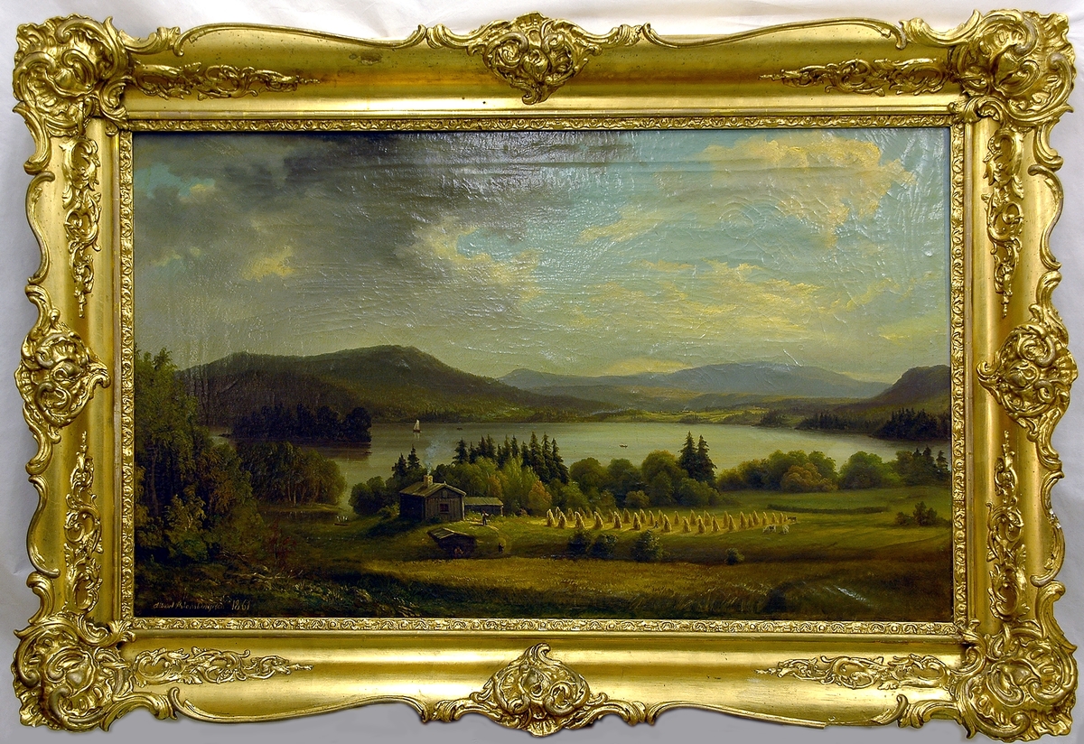 Montering/Ram: Förgylld originalram.
Oljemålning på duk. "Motiv från Bergviken" av Albert Blombergsson. Landslkap med insjö. I bakgrunden begränsad av berg och höjder; en gård skymtar där. I förgrunden en stuga och intill ett mejat sädesfält med sädeskärvarna satta skylar. Även ett ännu omejat fält. En kvinna kommer en jordkällare och en man springer och jagar bort några kor som kommit för nära sädesskylarna. Himlen delvis klarblå delvis molnig. Förgylld ram.