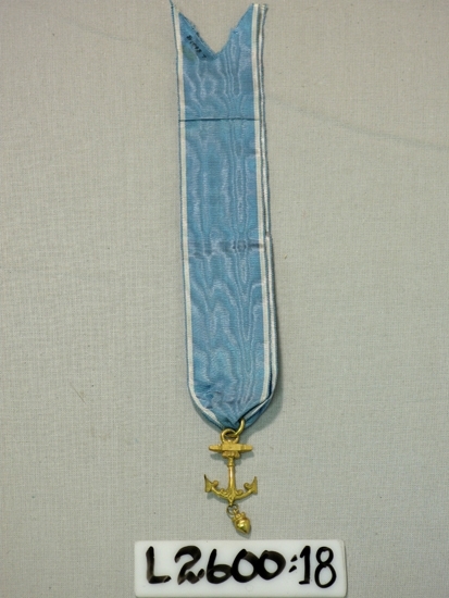 Ett 35 mm brett ripsband (vit-ljusblå-vit) med vidhängande 
förgyllt ankare.

Inskrivet i huvudboken 1933
Funktion: Ordenstecken