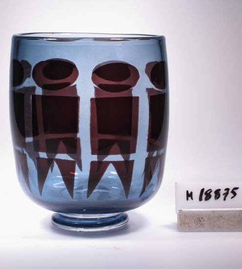 Vas.
Art.nr. Expo Sw 97-64.
Konstnär: John Selbing.
Beskrivning: Kupan (svagt) konvext cylindrisk. Avrundad nedtill, mycket kort ben, skivfot. Geometrisk dekor runt om.
Färg: Rökblå med rödbrun dekor. Klarglas.
Mått: Diameter ovan avser vasens övre diameter. Benets diameter: 48 mm. Fotdiameter: 59 mm. Ben- och fothöjd: 14 mm. Väggtjocklek: 4,5 mm.
Signerad. Se "Signering, märkning" ovan.
Inskrivet i huvudkatalogen 1966.
Funktion: Vas
