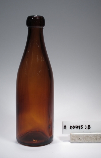 Cylindrisk.
Brun.
Text på glaset. Bokstaven "H" med en stjärna på vardera sidan. Ytterligare en stjärna ovanför. Bokstaven "C" (1924). Se "Signering, märkning" 1) ovan.
Märkning i botten. Se "Signering, märkning" 2) ovan.
Rester av etikett ("Signering, märkning" 3) ovan).
Inskrivet i huvudkatalogen 1968.
Funktion: Förpackningsflaska avsedd för öl.