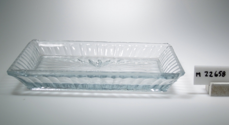 Serveringsfat.
Tillverkat på Sölvesborg, Sölvehyttan
Beskrivning: Rektangulär planform, utsvängda väggar. Imiterade oliver. Stjärna i botten.
Färg: Ofärgat klarglas.
Mått: Ovan angivna längd och bredd avser fatets övre mått. Bottenlängd: 172 mm. Bottenbredd: 110 mm.
Inskrivet i huvudkatalogen 1974.
Funktion: Serveringsfat