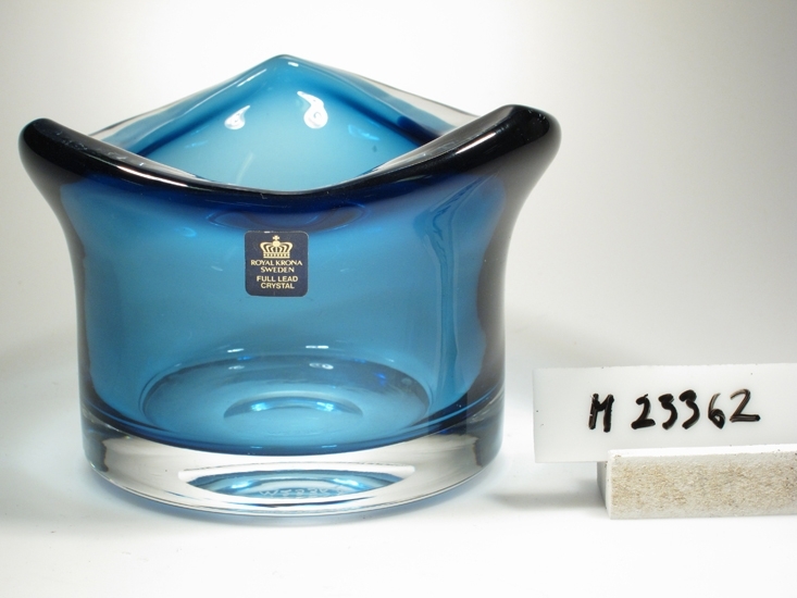 Vas. Tillverkad av Åseda glasbruk åt Kronabruken. 
Låg, cylindrisk med utsvängd, trekantig mynning, tjockt gods. Blått underfång.
Rektangulär, svart etikett med en krona och guldtext: "Royal Krona Sweden full lead crystal // Form Bo Borgström" 
Inskrivet i huvudkatalogen 1975.