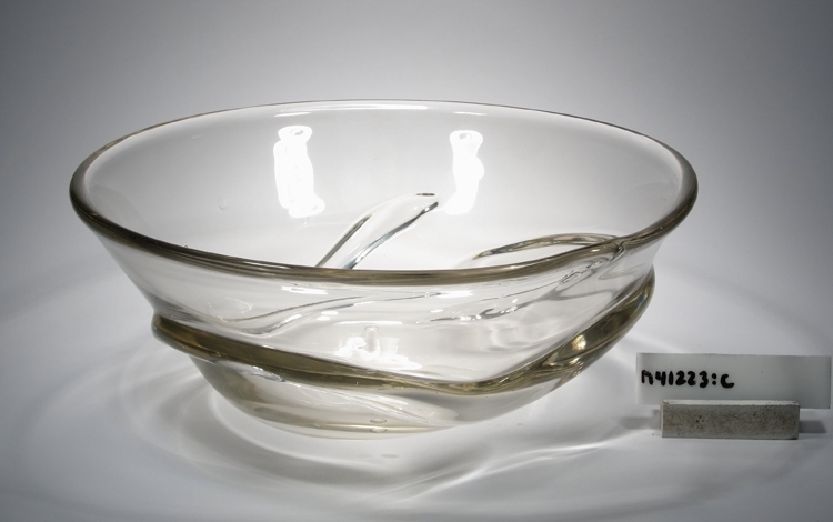 Ålskål. Formgiven av Hugo Gehlin. Se ritning.
Beskrivning: Klockformad med en ål virad runt om. Kulslipad botten.
Färg: Gråskimrande klarglas.
Mått: Ovan anges höjd och övre diameter. Bottendiameter: 96 mm.
Graverad märkning samt vit lapp med text. Se "Signering, märkning" 1 och 2 ovan.
Inskrivet i huvudkatalogen 1980.

Hugo Gehlin (1889-1953), verksam på Gullaskrufs glasbruk 1930-1953.
Funktion: Ålskål