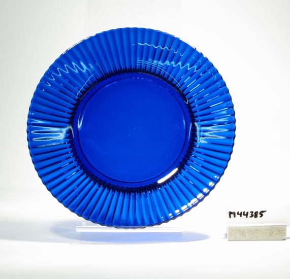 Tallrik. 
Beskrivning: Rund, svagt veckad kant med täta skär.
Färg: Blått klarglas.
Mått: Ovan angivna mått avser övre diameter. Bottendiameter: 127 mm.
Inskrivet i huvudkatalogen tidigast 1988.

Foto finns i arkivet.
Funktion: Tallrik