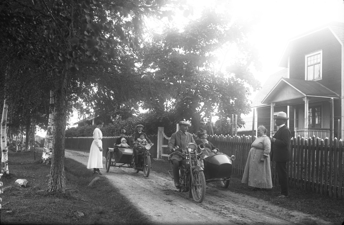 En A5770 Harley Davidson 1921 med Karl J T Lönnholm, statsskogvaktare, Stockholm, och en Indian 1916. Motorcykel två körs av John Svensson. Bredvid sitter hustrun Kerstin. I knä på John sitter sonen Göran och i knä på Kerstin sitter dottern Sonja. Mannen och kvinnan till höger i bild är Jon Svensson och hustrun Beda. Kvinnan till vänster är Johns syster Elin. Elin död 1965.