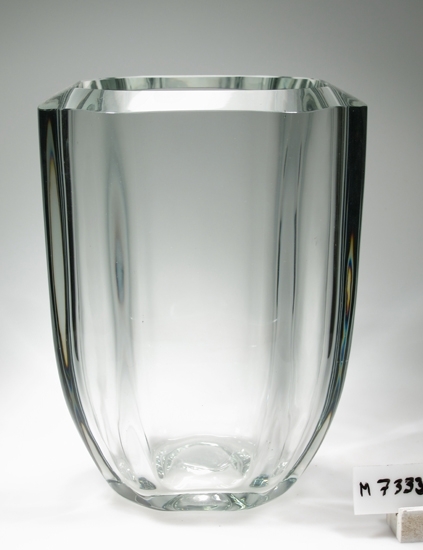 Blomvas.
Tjockväggig, 8-kantig, blåst i form med slipad sluttande kant.
Svartgrå degelfärg. (915)
Enl. reg.kort Kalisglas.
Funktion: Blomvas