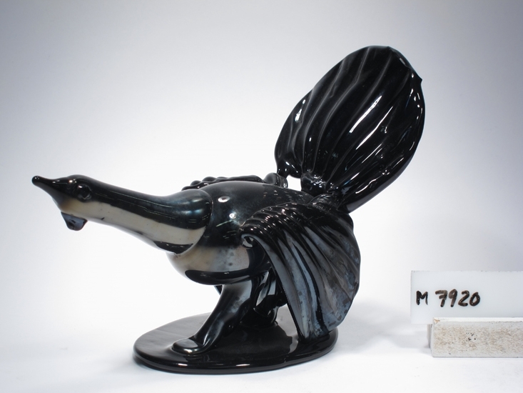 Tjäder av glas. 
Blåst av Ragnar Johansson ? (el. Karl Helge).
Beskrivning: Räfflade vingar och stjärt.
Färg: Svart, något iriserande. Opak.
Inskrivet i huvudkatalogen 1935.

Ragnar Johansson, verksam på olika glasbruk 1915-1928. 
Djur började han med på Björkshult, anställd där 1928-1950.
Funktion: Tjäder av glas