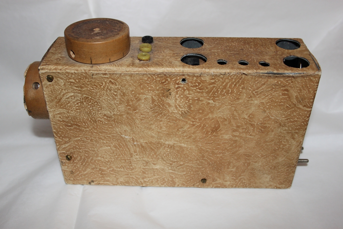 Radiomottaker, hjemmelaget. Rektangulært chassi laget i trefiner.. Med sorte høretelefoner med stempel OMEGA. Dette eksemplaret er fortsatt i utmerket stand. Det følger også med en improvisert antenne.