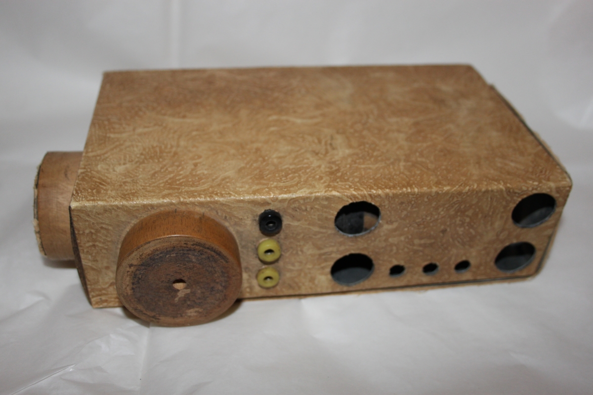 Radiomottaker, hjemmelaget. Rektangulært chassi laget i trefiner.. Med sorte høretelefoner med stempel OMEGA. Dette eksemplaret er fortsatt i utmerket stand. Det følger også med en improvisert antenne.