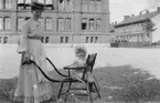 Ingegerd Hallgren drar barnet i en barnstol med hjul. Våren 1904