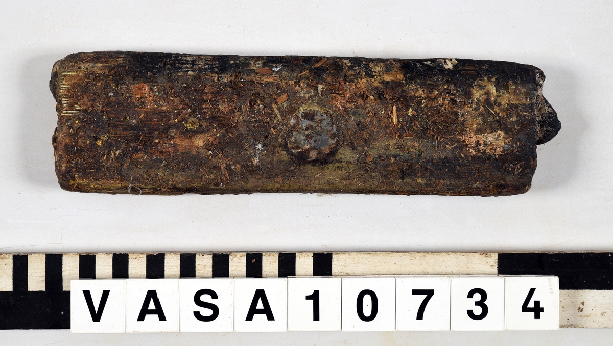 Odekorerad rektangulär bräda med ett spikhål. Tapp på båda ändarna möjlig spont på långsidan. Mycket vittrad yta. Kraftig saltskada (Salt 4) Tapparna avsplittrade.