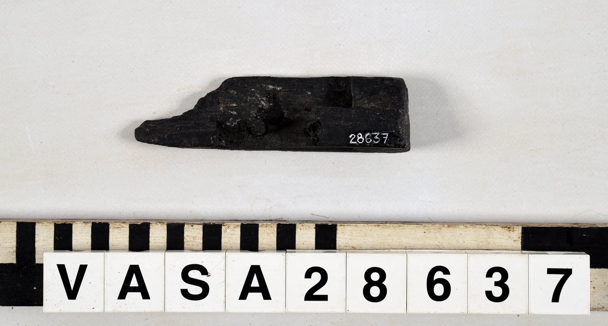 Avbruten del av ram, med rektängulärt urtag för att sammanfoga föremålet med ett annat föremål. Två pluggar är kvar i urtaget.  Nästan halva föremålet avsplittrat. Insidan på urtaget välbevarat med räta vinklar.