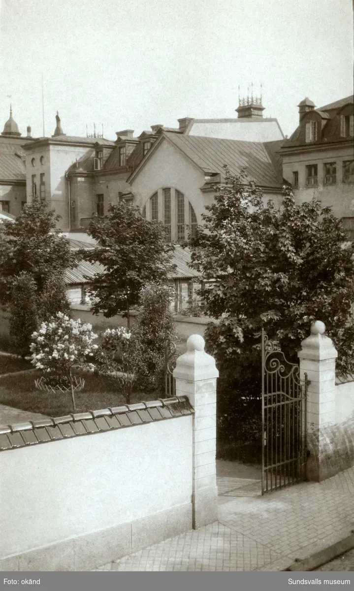 Bakgård samt grind till Riksbankens hus på Storgatan 29 (uppfört 1906-08). Badhusets karaktäristiska fönster ses skymta i grönskan.