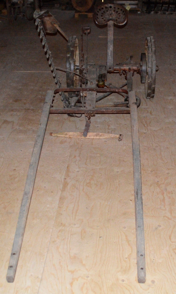 Slåmaskin for hest med drag. 6-eika metallhjul. Sete. Jarn, utan draget, som er i tre.