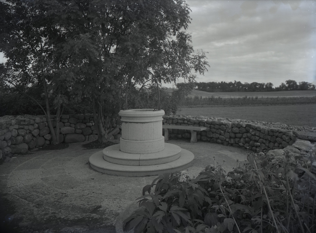 Bergagården, trädgården med brunnen och stenmur.