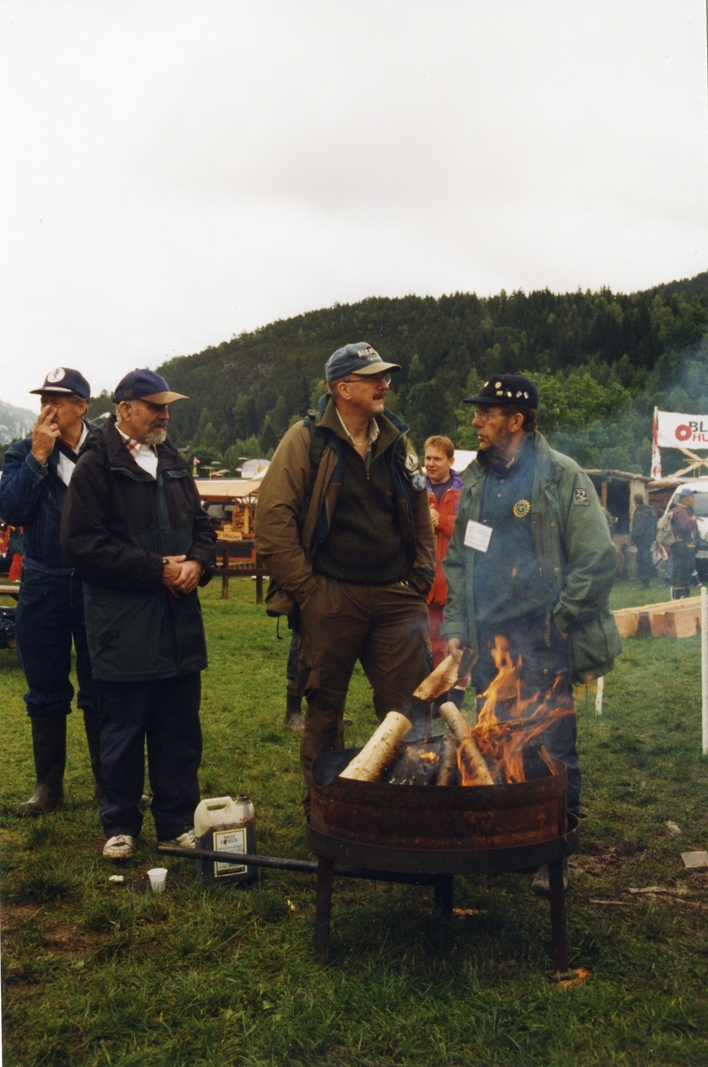 Folk varmar seg på bålpanne