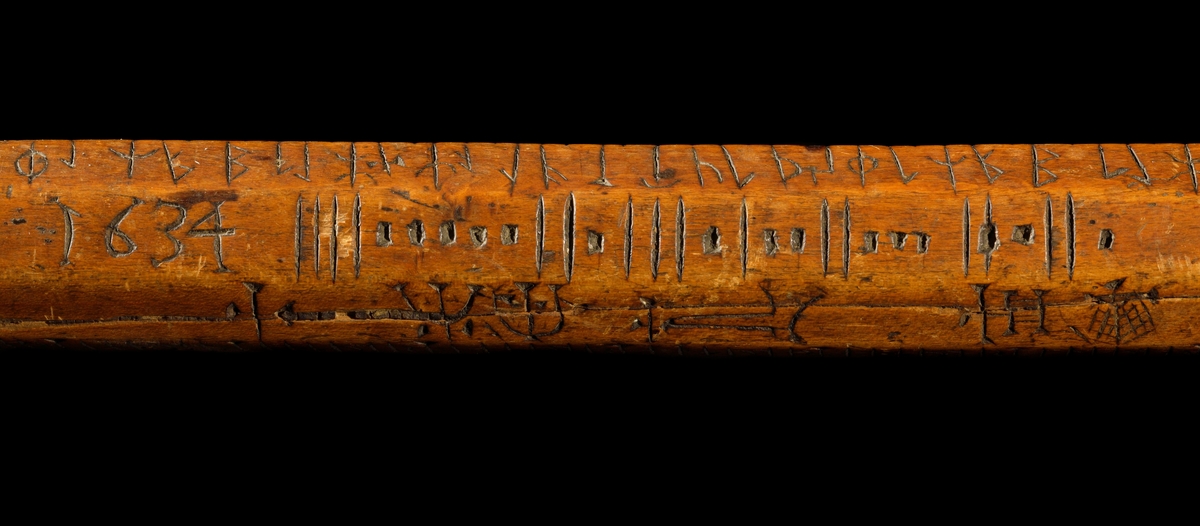 Kalenderstav i form av åttkantig, stavformad runkalender. 
Det korta handtaget har en balusterformigt utförande, med vertikala spetsar runt tvärgående band. Initialer: L P S och inskriptionen 1634 under handtaget och svagt på stavens ände.

S:t Peders lek (med korrektur). En gammal utslagningslek som går ut på att skilja vänner från fiender. Med hjälp av stavens markeringar kunde lekledaren i hemlighet räkna ut vilka personer som skulle slås ut. Namnet syftar på aposteln Petrus roll som himmelrikets portvakt, där han skiljer hedningar från kristna.