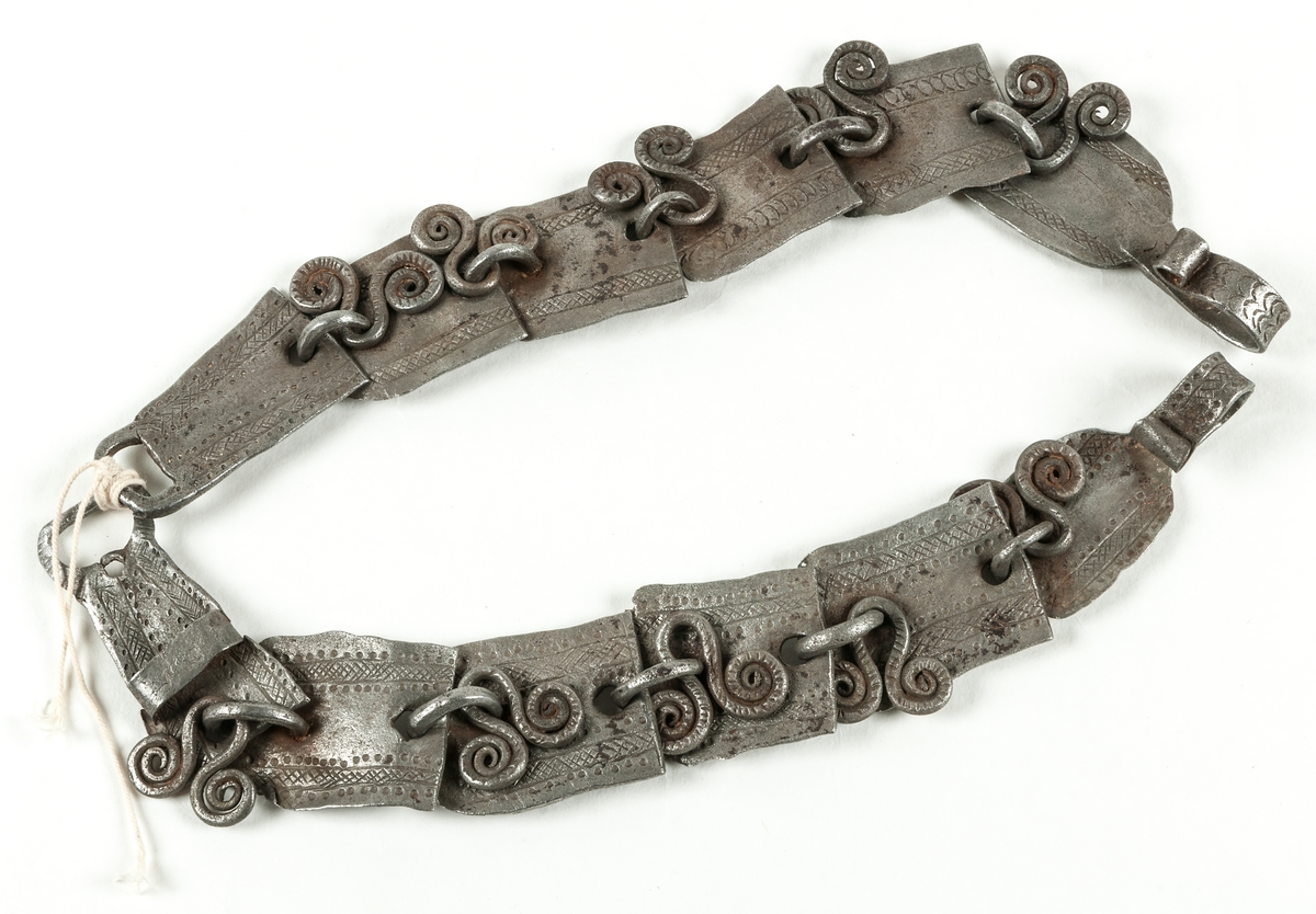 Halsband för nötkreatur sammanfogat av smidda länkar med öglor. I öglorna är sammanlagt tio stycken så kallade trollkors infogade. Detta för att skydda djuren från trolldom och onda väsen.

Enligt gammalt katalogkort: "Kobindsle gjort av järnplåtar med graverad ornering, punkter och rutnät, med hysklika järnprydnader vidhängande. Krok i ena änden. Oviss användning. Lappskt?"