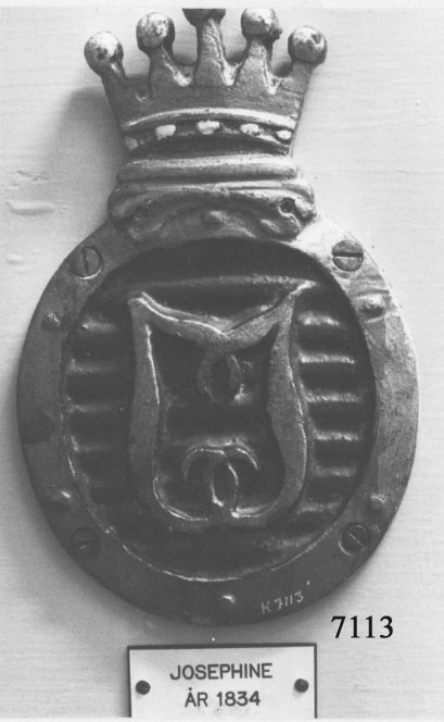 Emblemet är ovalformat med en kunglig krona på överkant i färgerna gult, blått, rött och vitt. Inom ovalen finns två J i relief, sammanflätade.
Har använts som stävmärken på fartygets småbåtar.