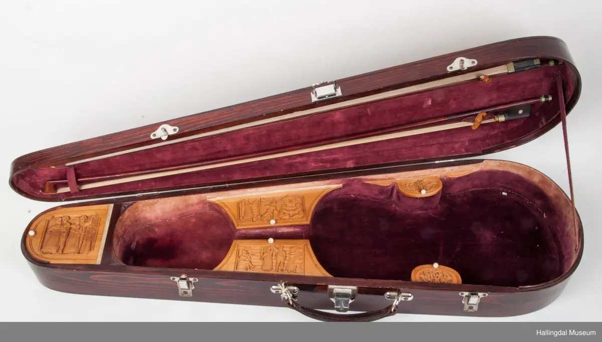 Lokket er utskjært med drake og båndslynginger.  Utskjæringer inne i felekassen.  5 rom med lokk i kassen.  3 lokk har utskjæringer med motiver fra hallingdans.  
Skaftet er besatt med perlemor, rosetegning i sort, dyrehode øverst på skaftet.  4 strenger over og 4 strenger under strengbrettet.  2 felebuer rødbrun mahogni.  Fela se HFN 03210.