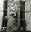 Undrar just vart tomten tog vägen? En liten pojke i randig pyjamas står på en stol och tittar ut genom ett fönster där det hänger en julstjärna av papper, julen 1949. På fönsterbrädan står en halmbock och mellan fönsterrutorna ligger vitlav.
