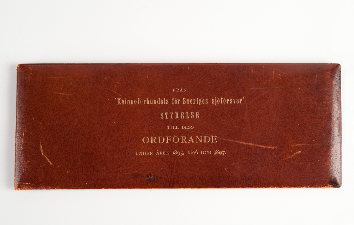 Läderetui med 16 medaljer med kvinnoporträtt i följande ordning (enligt maskinskrivet ark liggandes löst):
"Styrelsen för Kvinnoförbundet för Sveriges Sjöförsvar 1895-1897"
1. Amiralinnan Christersson
2. Fru Anna Wallenberg
3. Fru Coralie Elliot
4. Fru Landshöfdingsk. Emma Dyrssen, f. Fock
5. Fru Juel f. Björkman
6. Fru Hildegard Elliot f. Stråhle
7. Fru Ebba v. Eckerman f. Grevinnan v. Hallwyl
8. Fru Lannerstierna f. Almgren
9. Grevinnan Lotten Hamilton f. Beck-Friis
10. Fru Charlotte Wessäll f. Lewnhaupt
11. (tomt)
12. Fru Ida Carlstedt
13. (tomt)
14. Fru Wrangel f. Hallberg
15. Friherrinnan Ingeborg Hermelin f. Strömberg
16. (tomt)