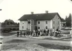 Björkshult 1911, bostadshus med putsad fasad. Folksamling framför byggnaden.