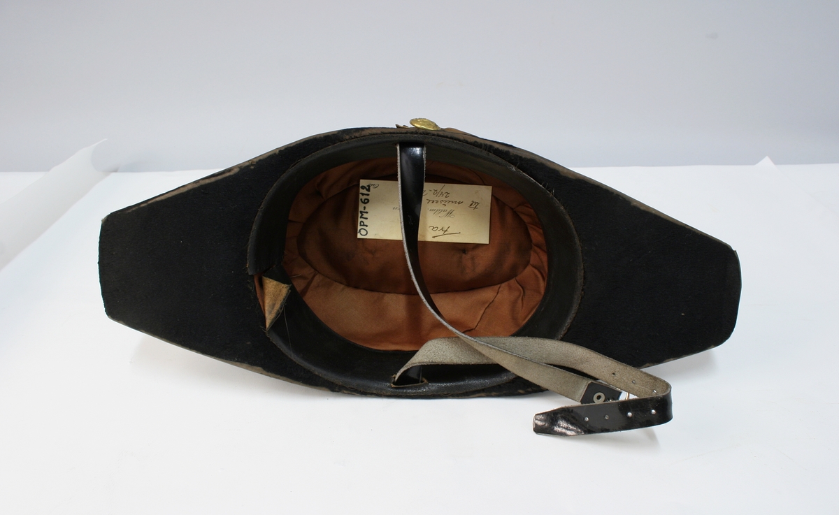 Hatten har nasjonalkokarde, krampe og besetning av possementsarbeid i gull.