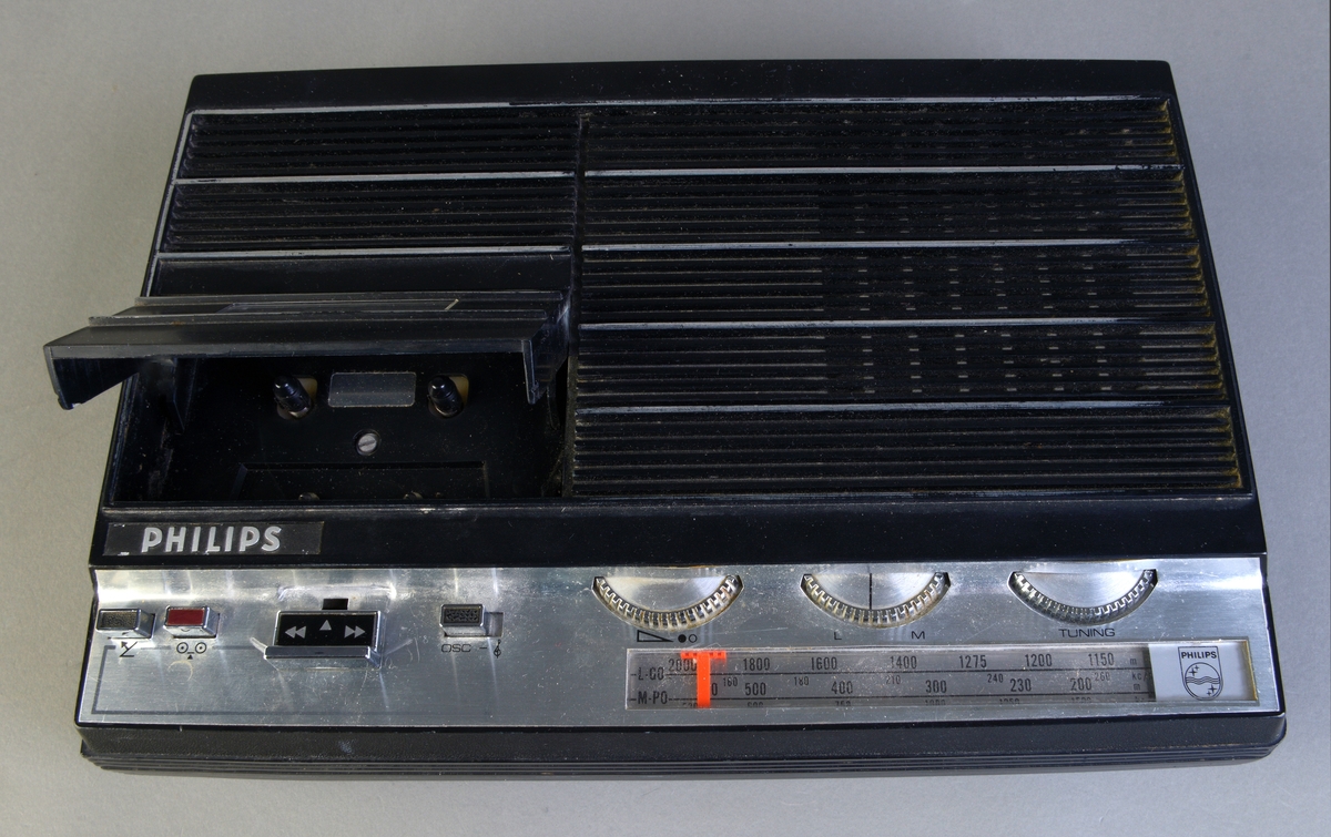 Kasettspiller med radio og tilhørende mikrofon (henholdsvis FTT.53948.01 og FTT.53948.02) fra Philips.
Kasettspilleren med radio er svart med detaljer i sølvfarge. Den er laget av plast og metall. Området for knapper og radio er sølvfarget. Knappene til kasettspilleren er sølv, svart og rød. For volum, lyd og tuning er det sølvfargede hjul. Kasettspilleren kan gå både på batteri og på strøm. Det er rom for batteri er på undersiden, mens uttak for strøm er bak på spilleren. Det er også to andre uttak på baksiden.
Mikrofonen ligger i en pappeske. På esken er det bilde av en mikrofon med en person som spiller xylofon i bakgrunnen. Mikrofonen er grå, sølvfarget og svart. Den er laget av metall og plast. på toppen er det et metallgitter. Ledningen til mikrofonen er svart. Det følger også med en "hette" til mikrofonen i svart skumgummi, samt et stativ i metall.