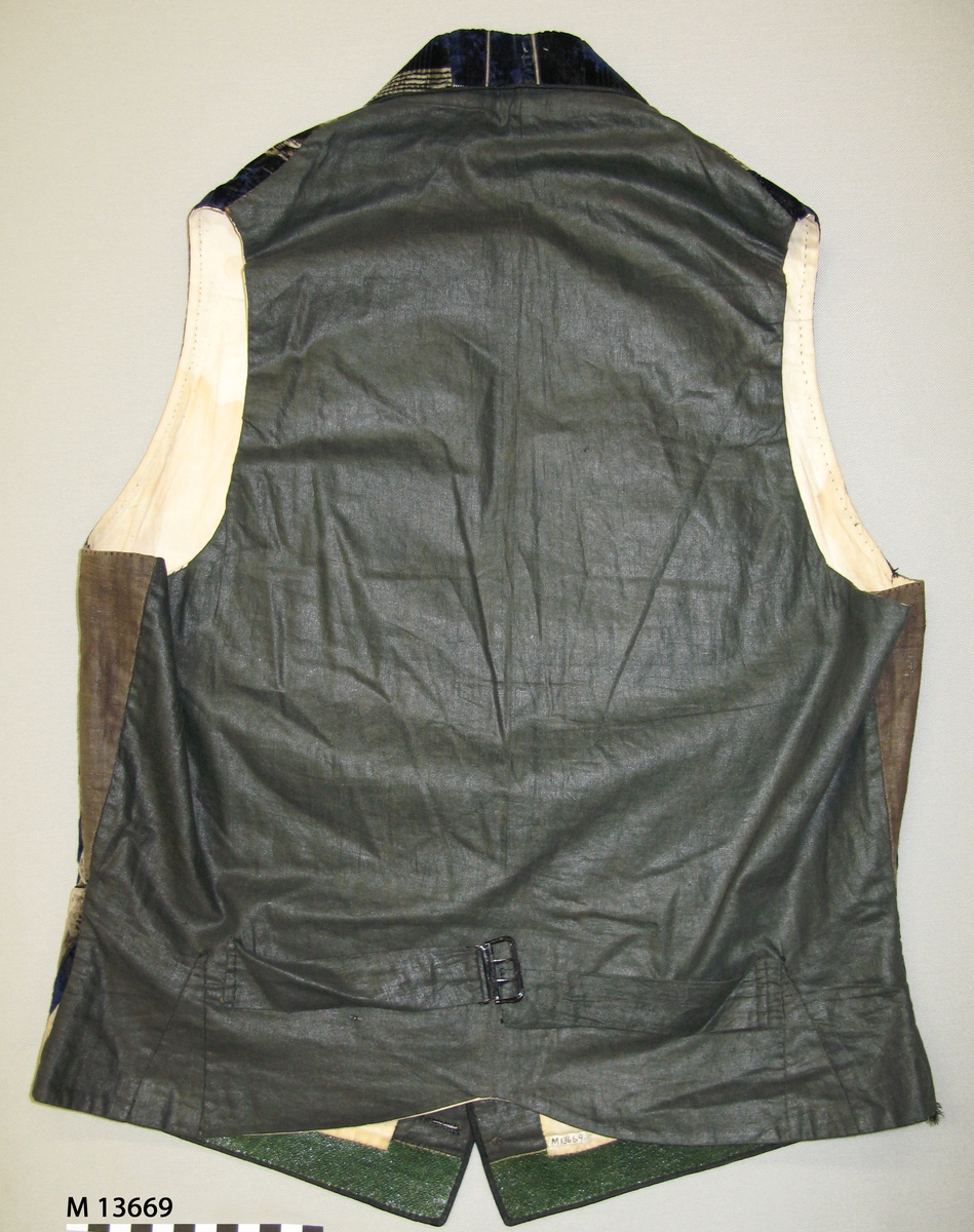 Blå/beige/brun rutig blomranksmönstrad sidensammet. Framsyckena är vadderade. Sammeten är mönstrad i skuren och oskuren sammet med värmeetsad skuren sammetslugg som bildar blomsterrankorna. Ripsbindning bildar rutorna. Vikt skarvad schalkrage och fyra blå trådklädda knappar i silke i öppning framtill. Infällda fickor på båda framstyckena. Tunt svart vaxat bomullstyg i bakstycket med slejf och metallspänne. Helfodrad med ljust linnefoder i tuskaft. Skodd med gröna skinnremsor på insidan av framkanternas nederkant.