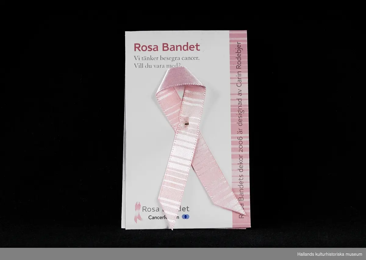 Fem stycken rockmärken, i form av "Rosa Bandet". Rosa "sidenband" vikt och sammansatt med liten säkerhetsnål. Bandet och en liten textbok ligger i en plastficka. Utvalda formgivare ger bandet varierat utseende varje år. 
a) 2006, Carin Rodebjer(trasmatta). b) 2007, Lars Wallin(kedja). c) 2008, Ingegerd Råman (text). d) 2009, Gert Wingårdh (blindskrift). e) 2011, Lena Ph, Per Holknekt (omfamning).