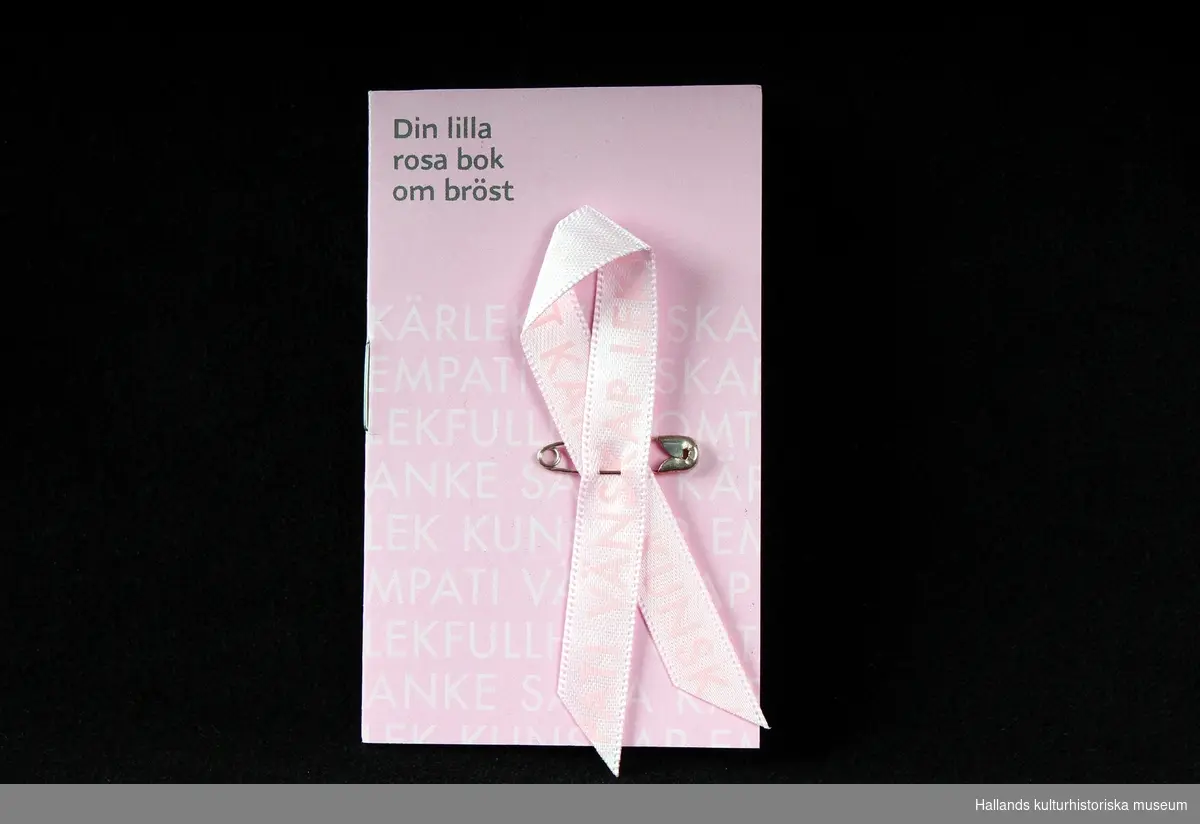 Fem stycken rockmärken, i form av "Rosa Bandet". Rosa "sidenband" vikt och sammansatt med liten säkerhetsnål. Bandet och en liten textbok ligger i en plastficka. Utvalda formgivare ger bandet varierat utseende varje år. 
a) 2006, Carin Rodebjer(trasmatta). b) 2007, Lars Wallin(kedja). c) 2008, Ingegerd Råman (text). d) 2009, Gert Wingårdh (blindskrift). e) 2011, Lena Ph, Per Holknekt (omfamning).