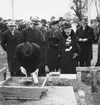 Grundstenen för Gävle Museum lägges 26 oktober 1938. Här ses borgmästatare Nils Berlin övervaka när en person håller i mursleven. Kvinnan till höger i bild är fru Normelli (syster till Antonie Rettig) (Hon är identfierad från bild i Norrlandsposten torsdagen den 27 oktober 1938)