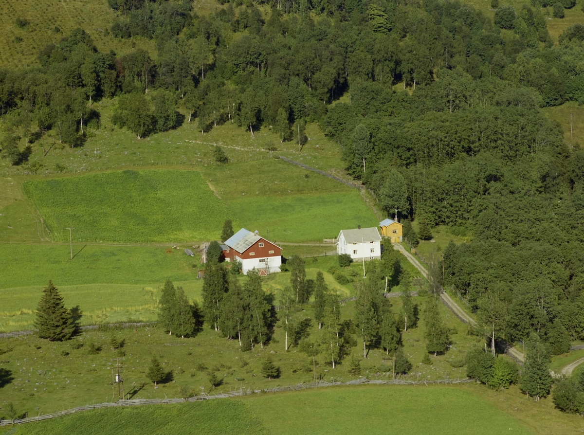 Østre Gausdal, med gården Bokstad. Et hvitt og et gult våningshus. Jorder og skog bak.