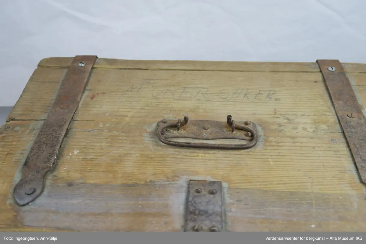 Teknikk: Spikret sammen av 11 1/2" ulimte bord slik at skrinets høyde, bunn og lokk har samme dimensjon ( 11 1/2"= 29,5 cm.)
Form: Rektangulær kasse med hengsler, låsbeslag og håndtak av jern.
En god del av malingen på kassen er flaket av.