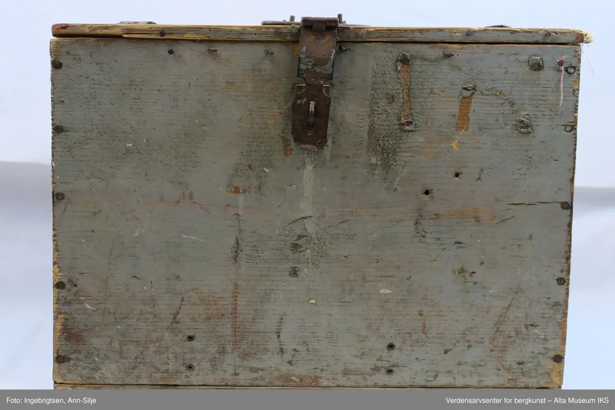 Teknikk: Spikret sammen av 11 1/2" ulimte bord slik at skrinets høyde, bunn og lokk har samme dimensjon ( 11 1/2"= 29,5 cm.)
Form: Rektangulær kasse med hengsler, låsbeslag og håndtak av jern.
En god del av malingen på kassen er flaket av.