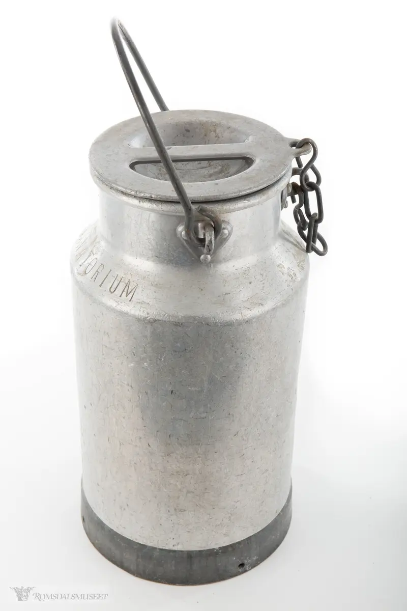 Melkespann i aluminium med lokk og hank. Lokket er festet i spannet med kjetting. Spannet har forsterket bunn.