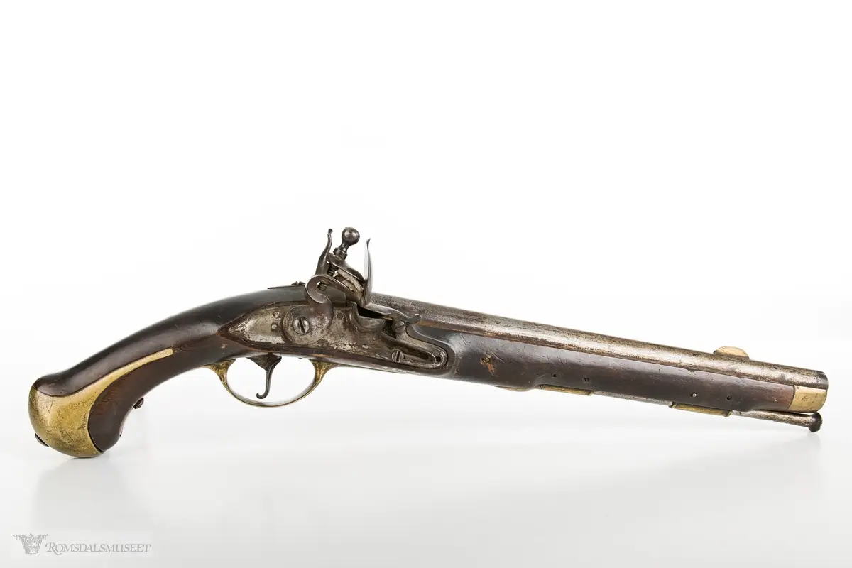Flintlåspistol med glattboret løp, uten baksikte og med åpent korn. Skjefte av bøk med messingbeslag i enden og ved munningen. To røkner med ladestokk.