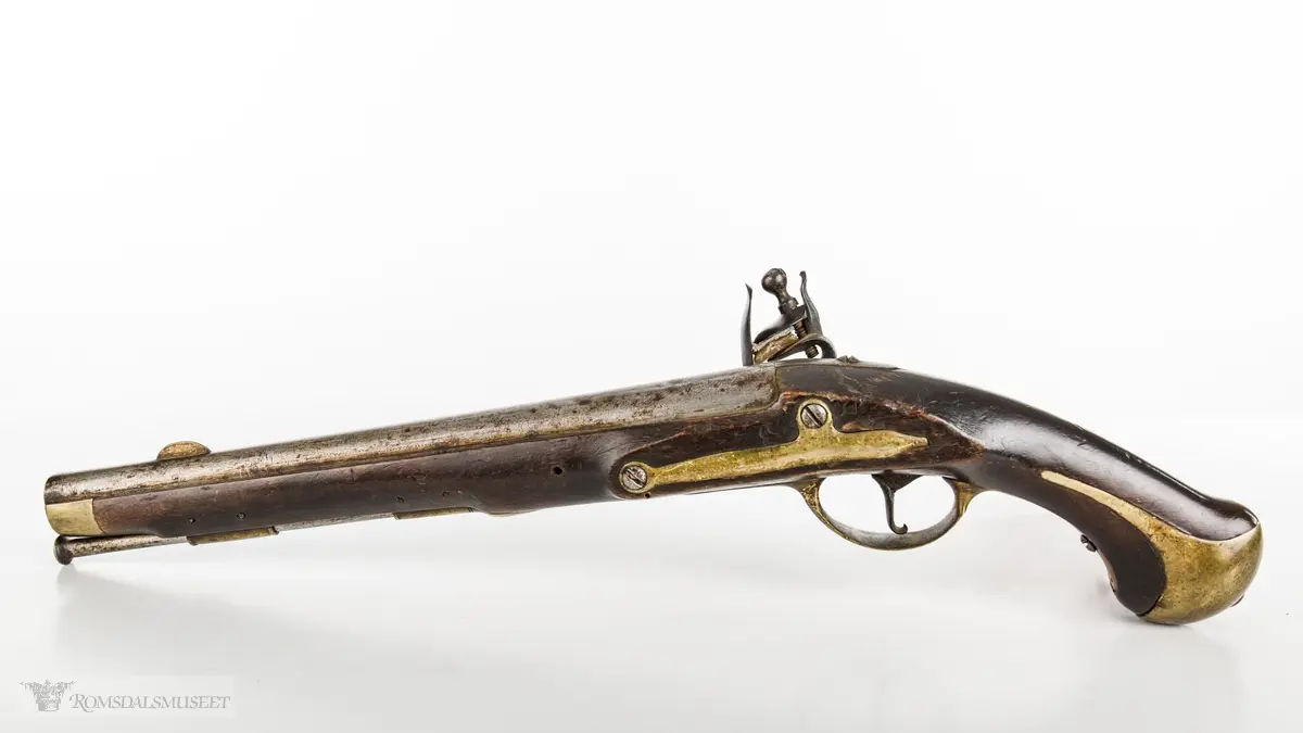 Flintlåspistol med glattboret løp, uten baksikte og med åpent korn. Skjefte av bøk med messingbeslag i enden og ved munningen. To røkner med ladestokk.