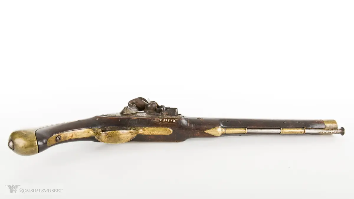 Flintlåspistol med glattboret løp, uten baksikte og med åpent korn. Skjefte av bøk med messingbeslag i enden og ved munningen. To røkner med ladestokk.