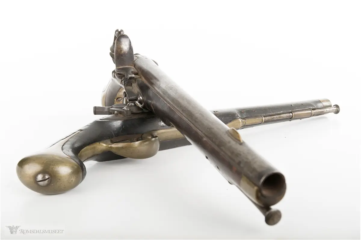 Flintlåspistol med glattboret løp, uten baksikte og med åpent korn. Skjefte av bøk med messingbeslag i enden og ved munningen. To røkner med ladestokk.