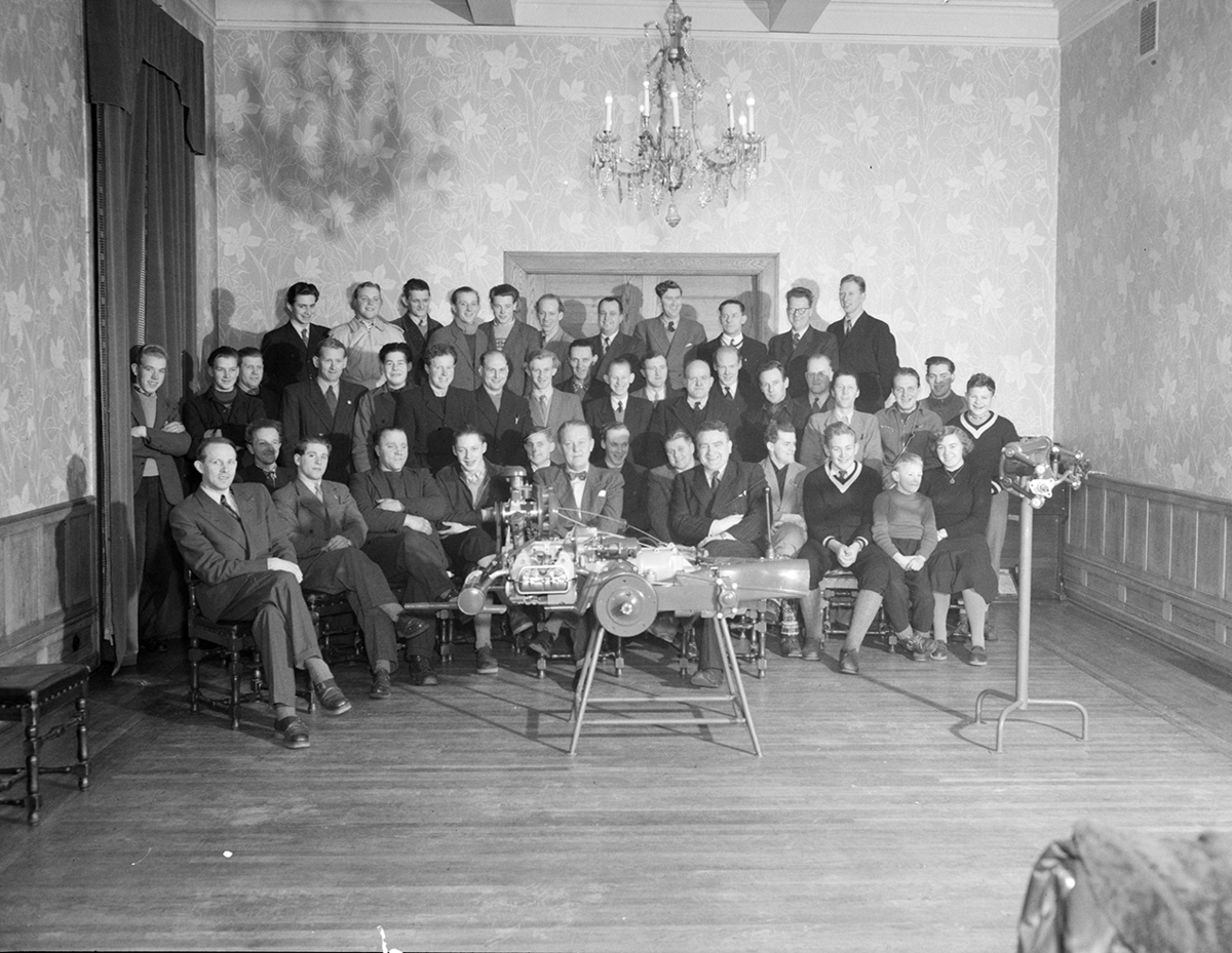 Hamar, Østregate 11 - 13, Ivar Olrud etablerte Olrud Auto i 1929, bilforhandler, bilverksted og bensinstasjon, Gruppe 40, anstatte og ledere, hele staben på kundeservicekurs. 1. rekke fra venstre nr . 9  Ivar Olrud. yngste deltakere var sønnene Ivar Wilhelm Olrud 15 år, Eivind Olrud 13 år og Jon Olrud 9 år, bilmotor i forgrunnen,