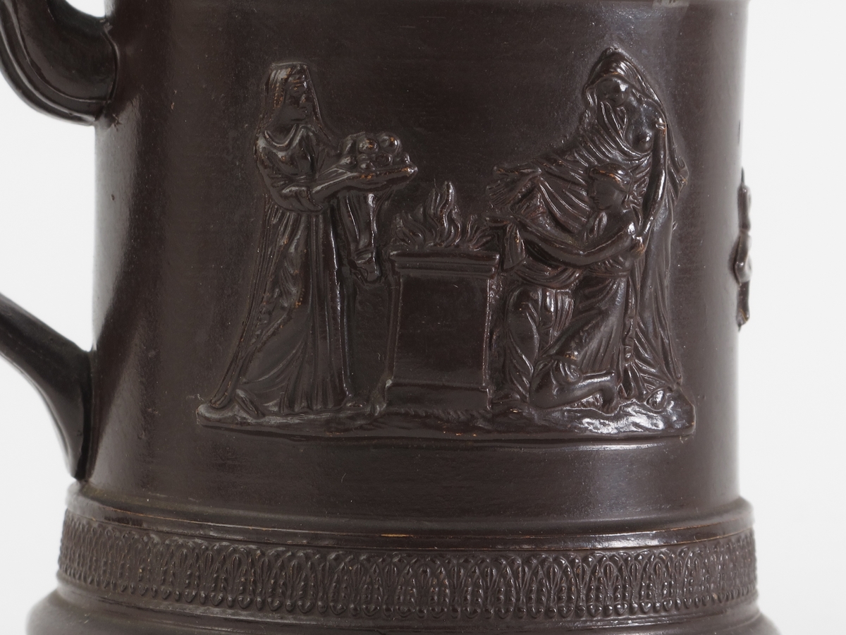 Th. for hanken 3 kvinner i klassiske gevanter ved et  arnested, pm. en oval rosett og tv. for hanken  kvinne får håret stelt, med to tjenerinner.