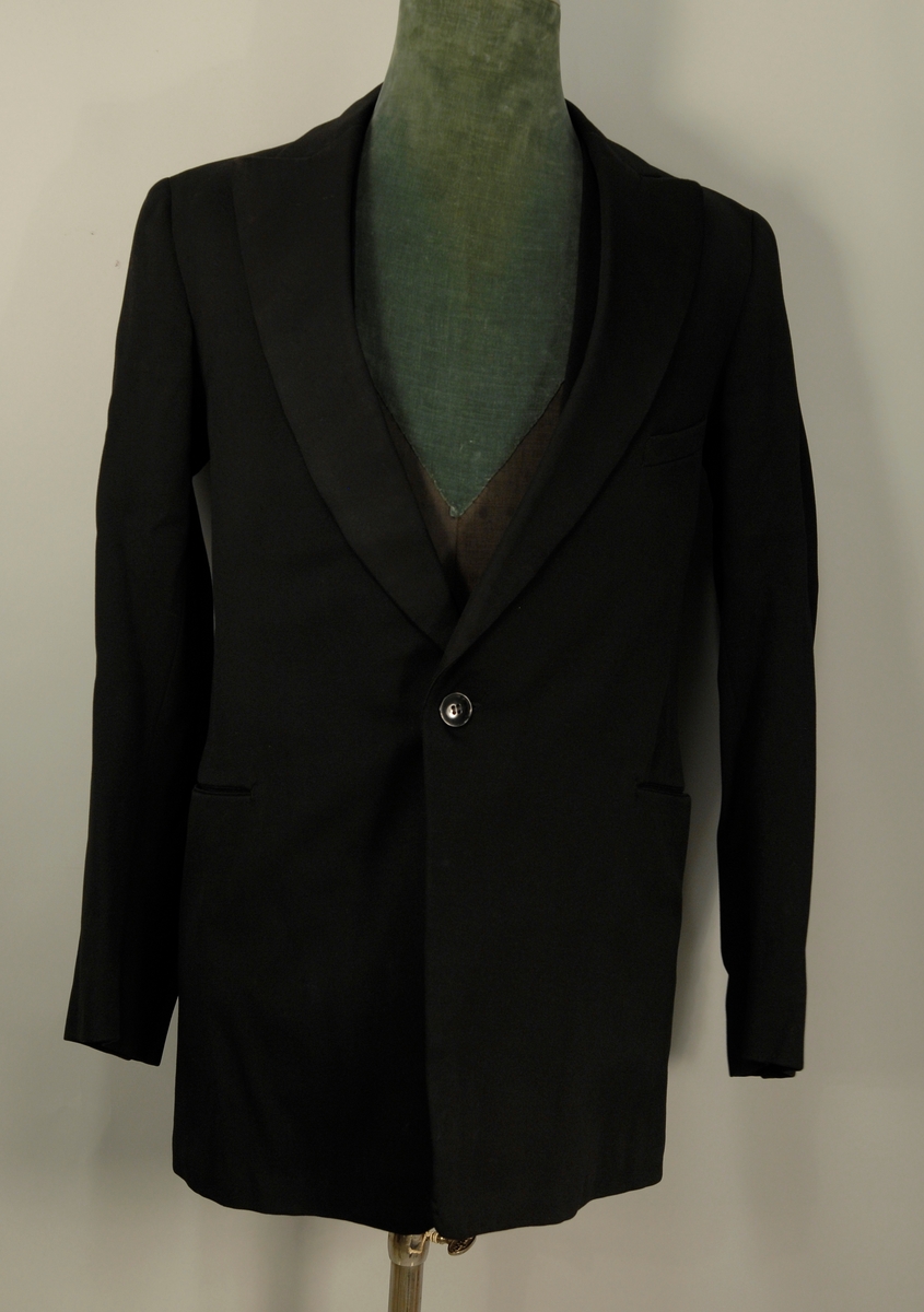 A: Jakke
Dyp V-formet halsskjæring, enkeltspent med ein knapp og knapphull. Spisse slag, kledd med diagonalvevd svart natursilke. Brystlomme og stikklomme i hoftehøgde i kvar side. Tosømserme med tre knapper. For av satengsvevd mercerisert bomull.

B: Bukse
Stikklomme øvert i kvar sidesøm og øverst i kvar sidesøm og øverts på høgre bakstykke. Gylf med skjult lukkning med tre knapper og knapphull. Splitt midt bak, liten trekantet innskjøtning, spensel med spenne. Linning 2 cm høg bak, 3,5 cm foran og lukkes med hekte. Seks blålige metallknapper for bukseseler i linningen som er foret med med kvitt satengvevd bomullstøy med trykte småfigurer.

C: Vest
Dyp. U-formet halsskjæring, enkeltspent med fire knapper og knappehull. Forstykkene avsluttes i spisser. Skråstilt stikklomme på v. forstykke, tilsvarende i livhøgde på kvart forstykke. Rygg av samme tøy som for i jakke. Splitt midt bak og i sidene. Spensel med spenne. Fór av samme tøy som bukse.