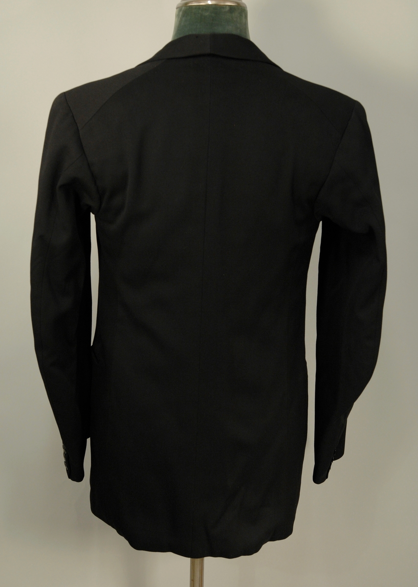 A: Jakke
Dyp V-formet halsskjæring, enkeltspent med ein knapp og knapphull. Spisse slag, kledd med diagonalvevd svart natursilke. Brystlomme og stikklomme i hoftehøgde i kvar side. Tosømserme med tre knapper. For av satengsvevd mercerisert bomull.

B: Bukse
Stikklomme øvert i kvar sidesøm og øverst i kvar sidesøm og øverts på høgre bakstykke. Gylf med skjult lukkning med tre knapper og knapphull. Splitt midt bak, liten trekantet innskjøtning, spensel med spenne. Linning 2 cm høg bak, 3,5 cm foran og lukkes med hekte. Seks blålige metallknapper for bukseseler i linningen som er foret med med kvitt satengvevd bomullstøy med trykte småfigurer.

C: Vest
Dyp. U-formet halsskjæring, enkeltspent med fire knapper og knappehull. Forstykkene avsluttes i spisser. Skråstilt stikklomme på v. forstykke, tilsvarende i livhøgde på kvart forstykke. Rygg av samme tøy som for i jakke. Splitt midt bak og i sidene. Spensel med spenne. Fór av samme tøy som bukse.