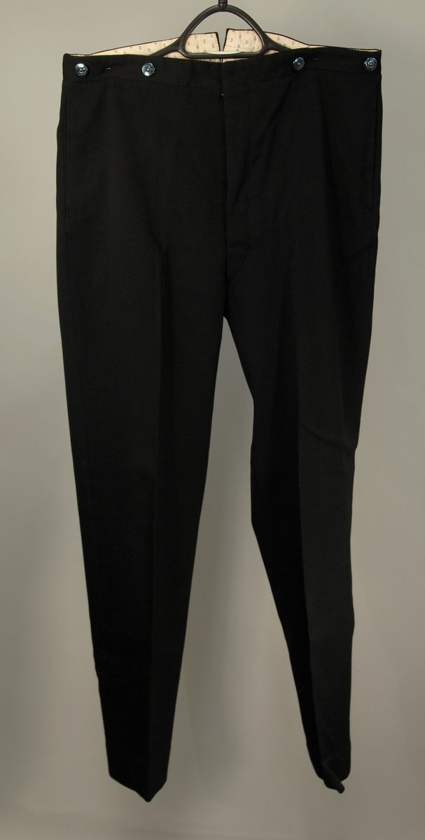 A: Jakke
Dyp V-formet halsskjæring, enkeltspent med ein knapp og knapphull. Spisse slag, kledd med diagonalvevd svart natursilke. Brystlomme og stikklomme i hoftehøgde i kvar side. Tosømserme med tre knapper. For av satengsvevd mercerisert bomull.

B: Bukse
Stikklomme øvert i kvar sidesøm og øverst i kvar sidesøm og øverts på høgre bakstykke. Gylf med skjult lukkning med tre knapper og knapphull. Splitt midt bak, liten trekantet innskjøtning, spensel med spenne. Linning 2 cm høg bak, 3,5 cm foran og lukkes med hekte. Seks blålige metallknapper for bukseseler i linningen som er foret med med kvitt satengvevd bomullstøy med trykte småfigurer.

C: Vest
Dyp. U-formet halsskjæring, enkeltspent med fire knapper og knappehull. Forstykkene avsluttes i spisser. Skråstilt stikklomme på v. forstykke, tilsvarende i livhøgde på kvart forstykke. Rygg av samme tøy som for i jakke. Splitt midt bak og i sidene. Spensel med spenne. Fór av samme tøy som bukse.