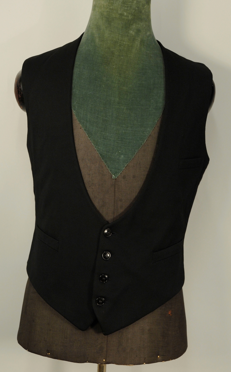 A: Jakke
Dyp V-formet halsskjæring, enkeltspent med ein knapp og knapphull. Spisse slag, kledd med diagonalvevd svart natursilke. Brystlomme og stikklomme i hoftehøgde i kvar side. Tosømserme med tre knapper. For av satengsvevd mercerisert bomull.

B: Bukse
Stikklomme øvert i kvar sidesøm og øverst i kvar sidesøm og øverts på høgre bakstykke. Gylf med skjult lukkning med tre knapper og knapphull. Splitt midt bak, liten trekantet innskjøtning, spensel med spenne. Linning 2 cm høg bak, 3,5 cm foran og lukkes med hekte. Seks blålige metallknapper for bukseseler i linningen som er foret med med kvitt satengvevd bomullstøy med trykte småfigurer.

C: Vest
Dyp. U-formet halsskjæring, enkeltspent med fire knapper og knappehull. Forstykkene avsluttes i spisser. Skråstilt stikklomme på v. forstykke, tilsvarende i livhøgde på kvart forstykke. Rygg av samme tøy som for i jakke. Splitt midt bak og i sidene. Spensel med spenne. Fór av samme tøy som bukse.